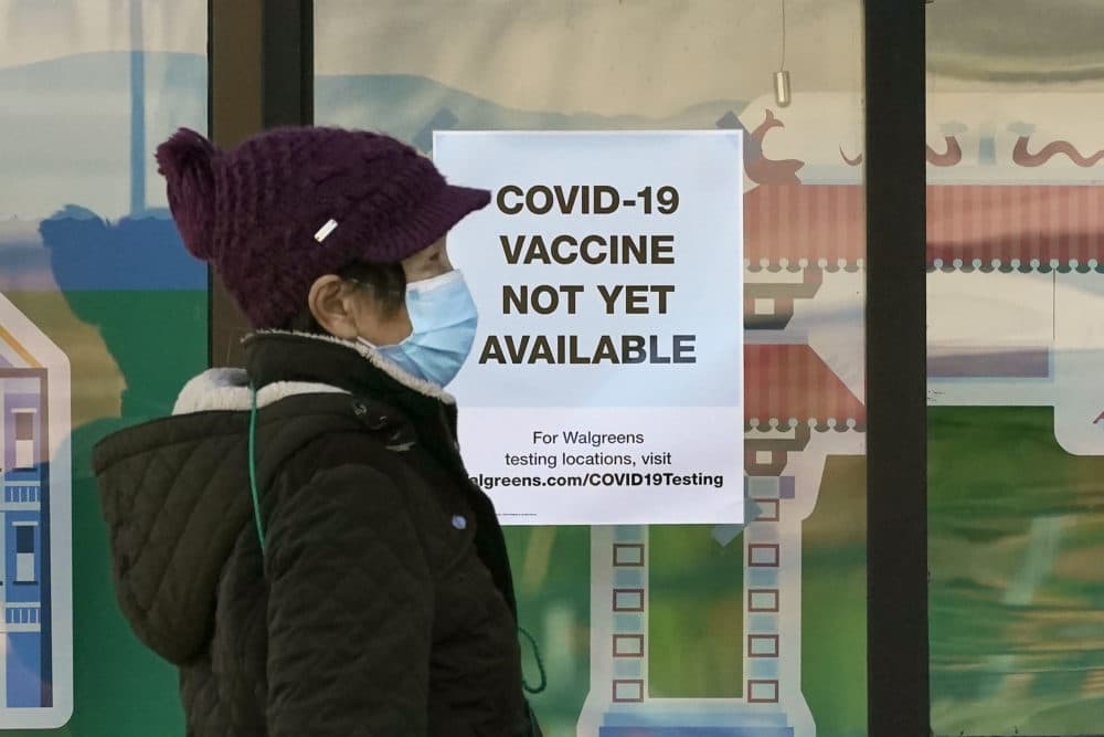 A pedestrian wearing a mask walks past a sign advising that COVID-19 vaccines are not available yet at a Walgreen's pharmacy store in San Francisco on Wednesday. (AP Photo/Jeff Chiu)