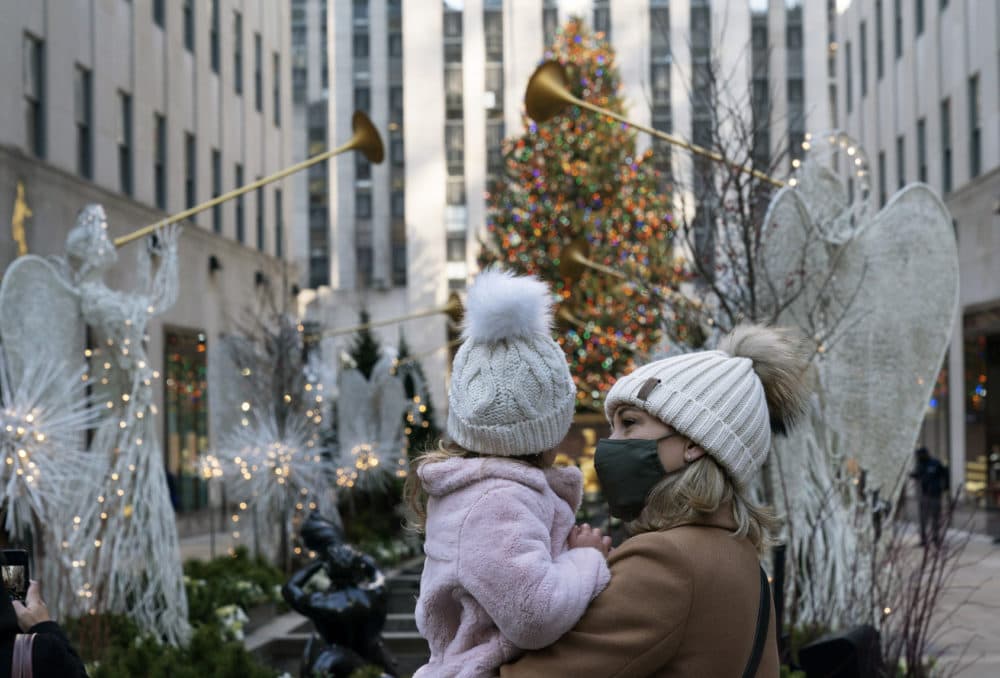 A woman holds her daughter as they look at the Rockefeller Center Christmas Tree, Thursday, Dec. 3, 2020 in New York. What’s normally a chaotic, crowded tourist hotspot during the holiday season is instead a mask-mandated, time-limited, socially distanced locale due to the coronavirus pandemic. (Mark Lennihan/AP)