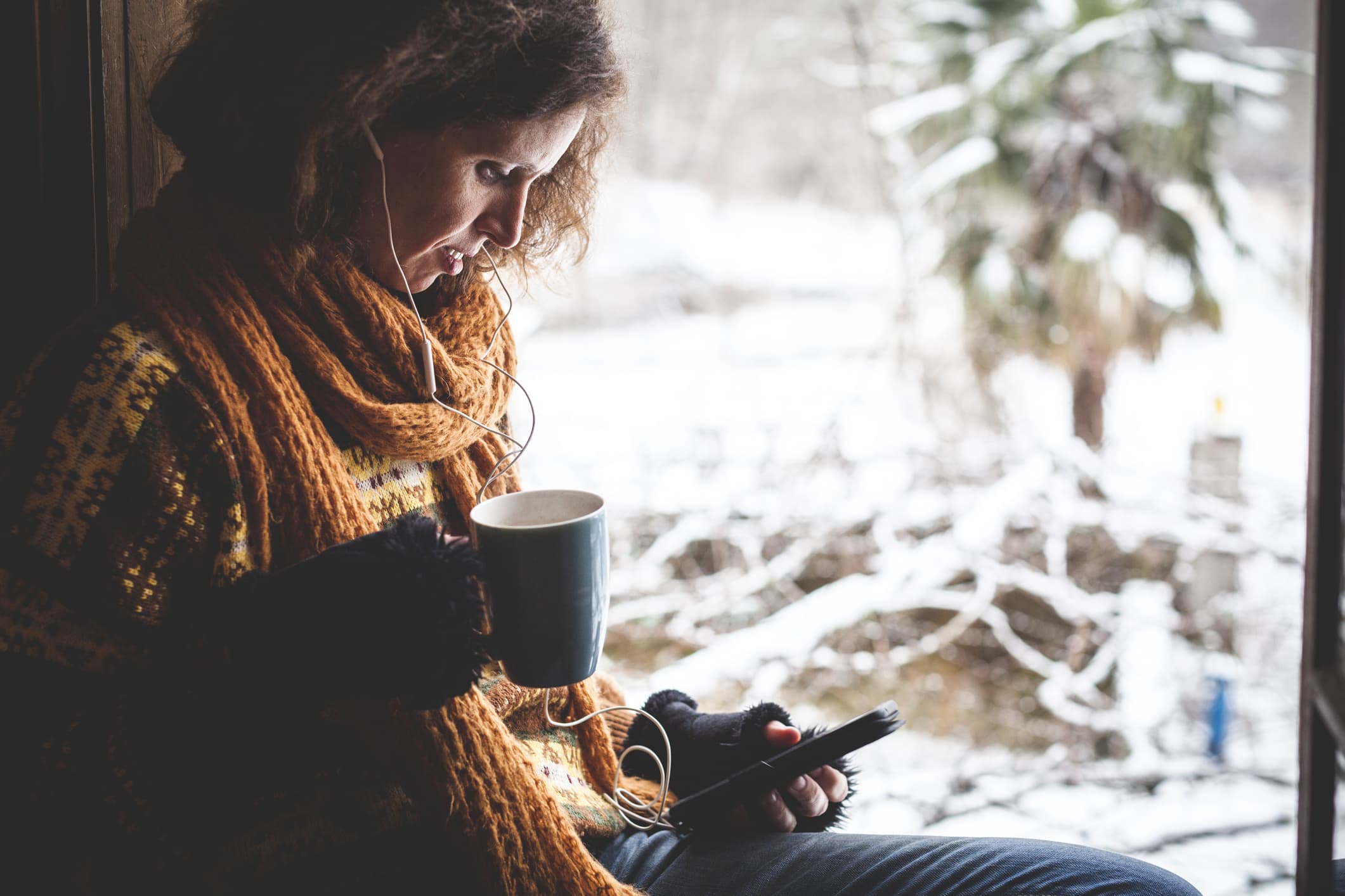 A woman listening to music as snow falls. (Getty Images)