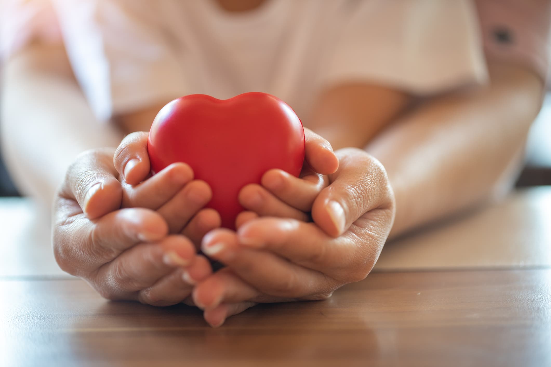 Adult and child hands holding red heart together. (Getty Images)