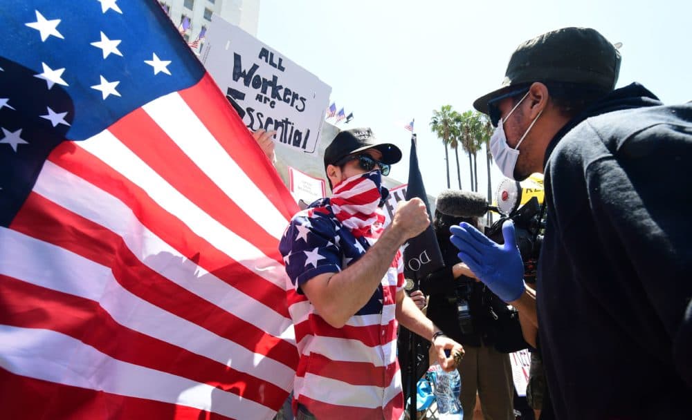 A protestor (L) argues with a counter-protestor (R) in front of the Los Angeles City Hall on May 1, 2020, to demand the end to the state's shutdown due to the coronavirus pandemic. (FREDERIC J. BROWN/AFP via Getty Images)