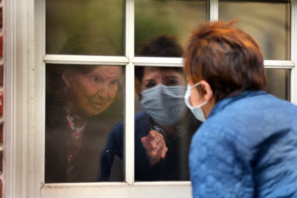 Ellen Taylor talks to her mother, Eva Taylor, age 100, through the first floor window in Jamaica Plain in Boston on May 8, 2020. The Rogerson House accommodated families that wanted to visit their mothers and grandmothers for Mothers Day. Because of coronavirus, family members have not been allowed inside. (John Tlumacki/The Boston Globe via Getty Images)