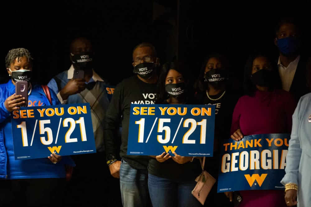 Family and supporters hold runoff signs as Democratic U.S. Senate candidate Rev. Raphael Warnock speaks during an Election Night event on November 3, 2020 in Atlanta, Georgia. (Jessica McGowan/Getty Images)