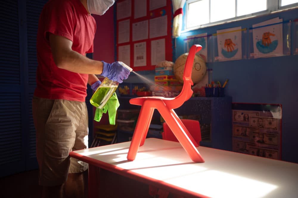 A person sprays disinfectant over kids' furniture. (stock photo via GettyImages)