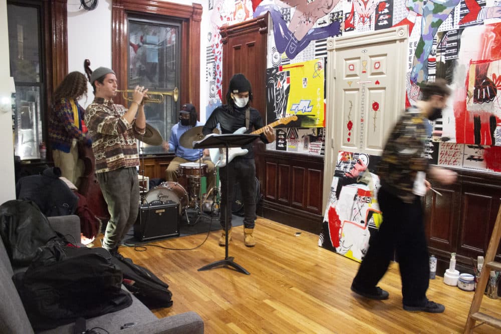 Fish paints to a live soundtrack as the band plays Thelonius Monk. From left to right: Caleb Ossmann on bass, Robert Vega on trumpet, Maliq Wynn on drums, and Mwanzi Harriot on guitar. (Jenn Stanley/WBUR)