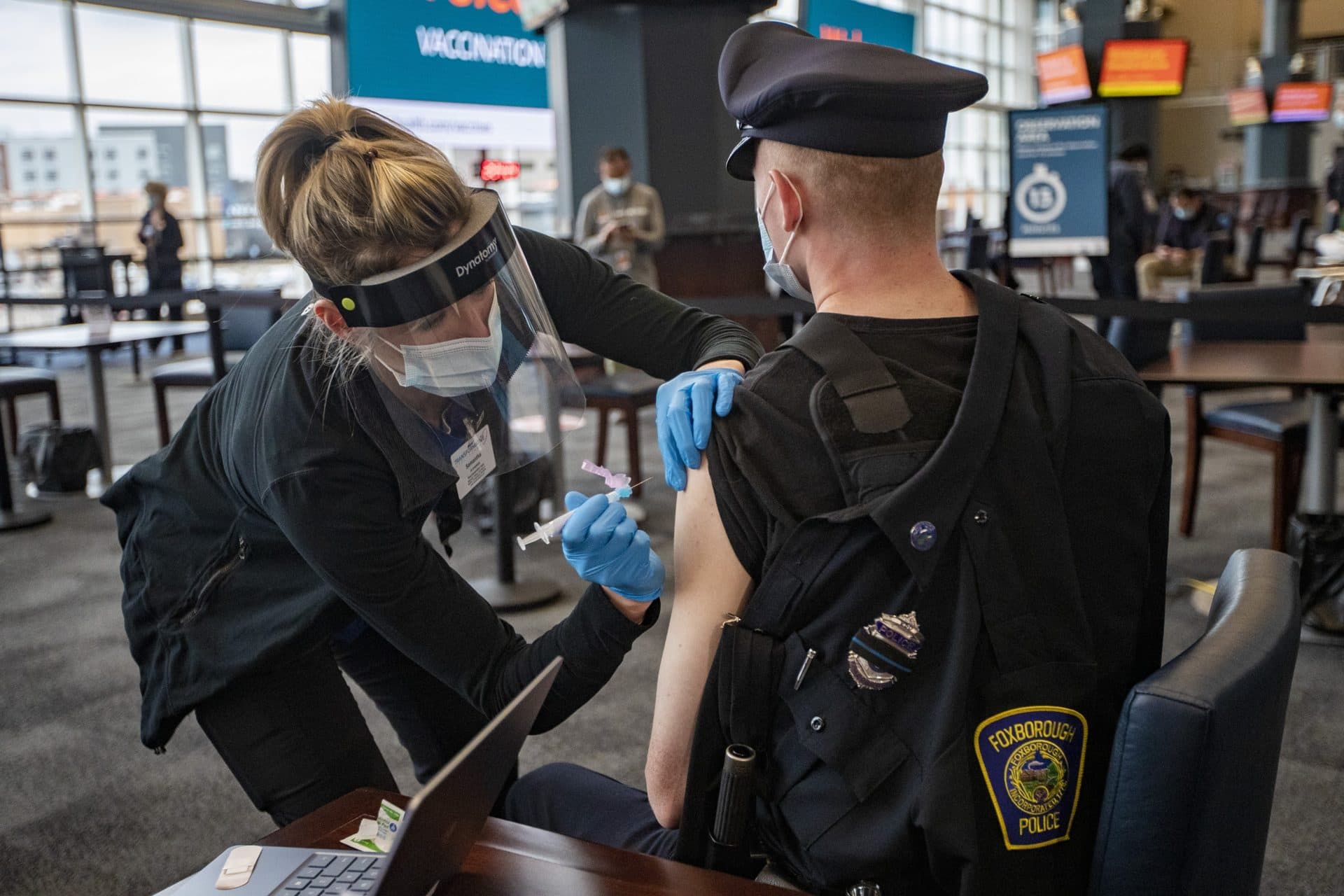 Registered nurse Samantha Schuko prepares to vaccinate Foxborough Police officer Brendan Fayles with the Moderna COVID-19 vaccine at the Gillette Stadium COVID-19 Vaccination Site. (Jesse Costa/WBUR)