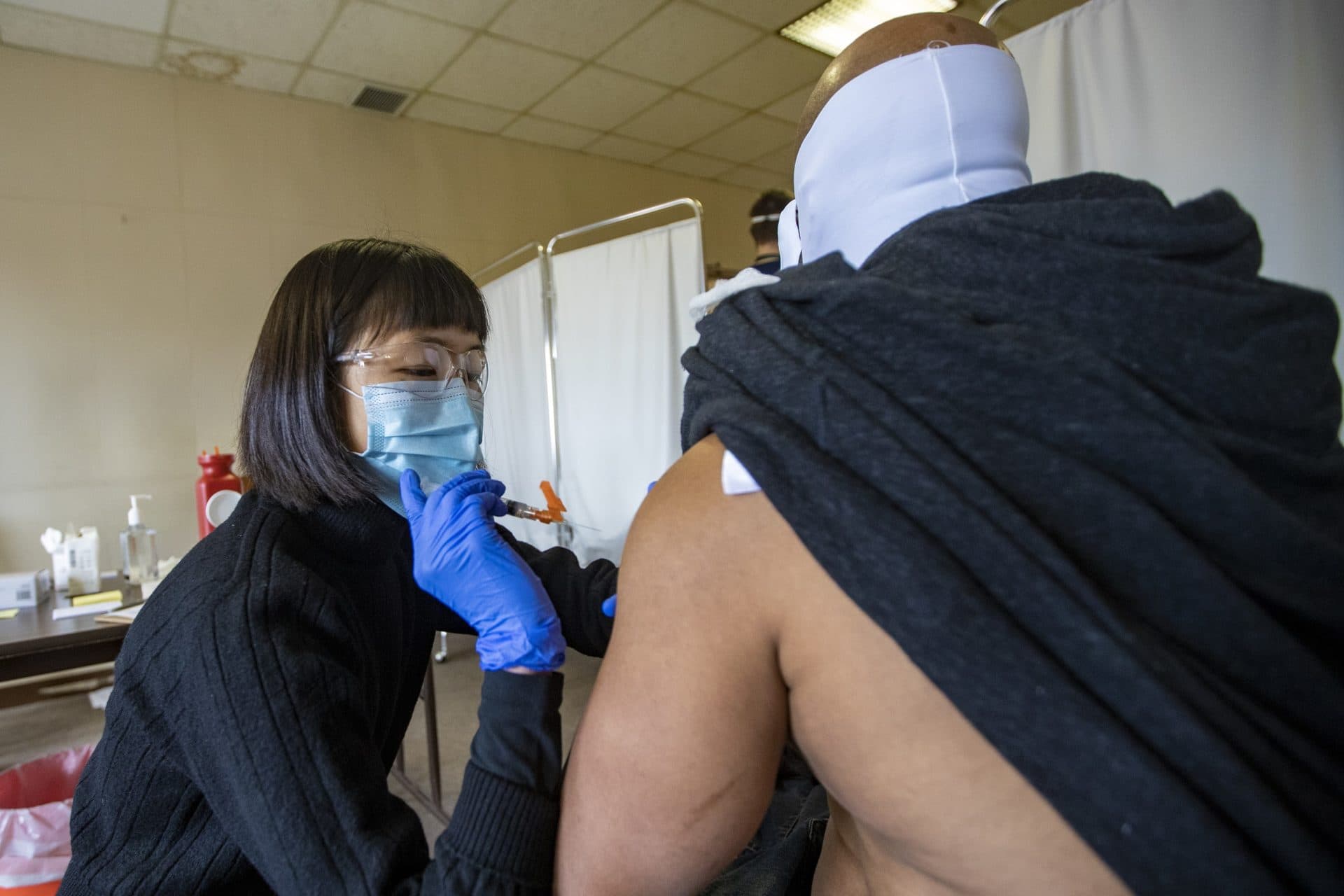 UMASS Medical School student Valerie Zhu administers the Moderna COVID-19 vaccine to Bobby Hammond, a client at Dismas House, at the Hotel Grace homeless shelter in Worcester. (Jesse Costa/WBUR)