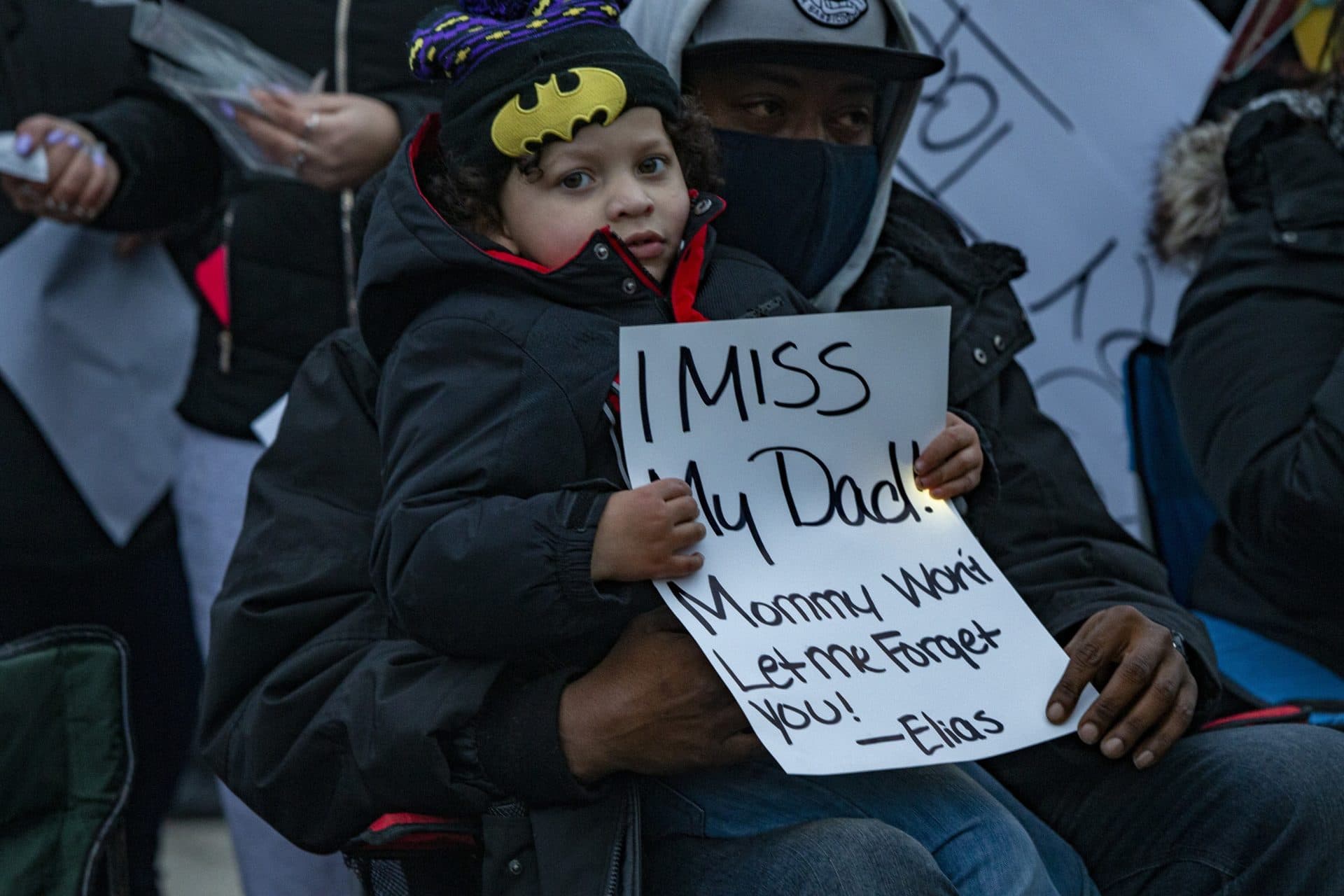 Henry Tapia’s son Elias Martin holds a sign that says “I Miss My Dad! Mommy won’t let me forget you” at a vigil honoring his memory in Cushing Square. (Jesse Costa/WBUR)