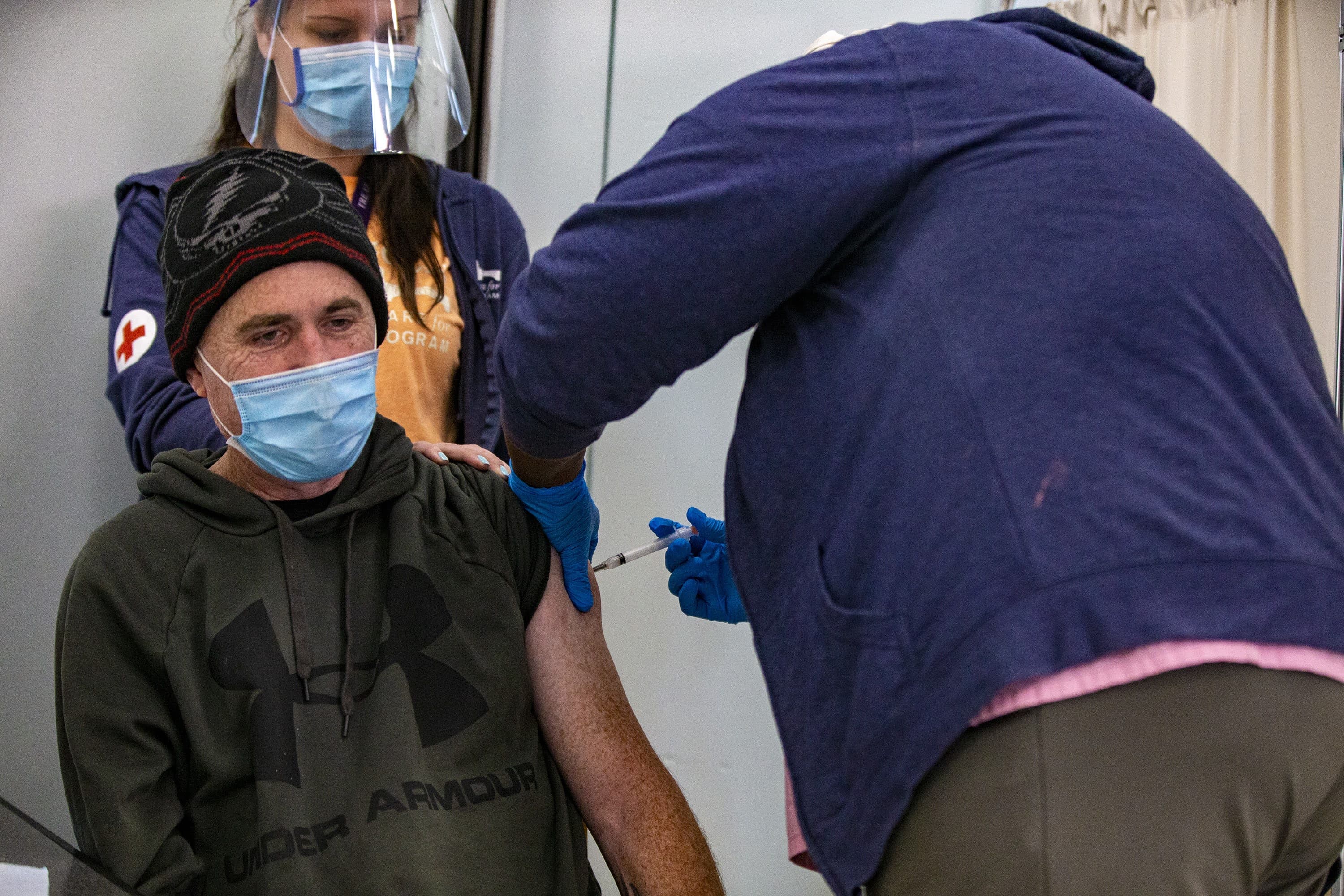 Jeffrey Davis, who's been staying at Pine Street Inn for 2.5 years, receives the COVID-19 vaccine from Boston Health Care for the Homeless registered nurse Ann Worrell. (Jesse Costa/WBUR)