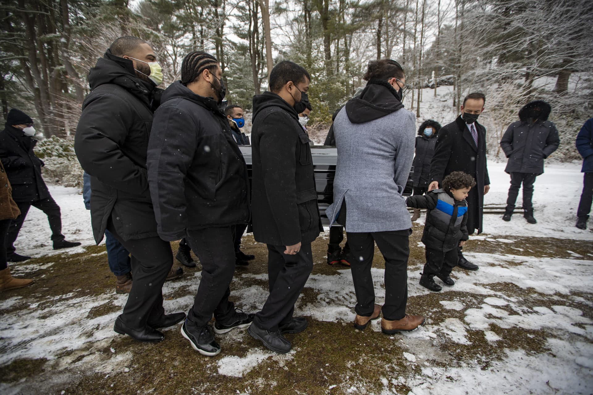 Henry Tapia’s 3-year-old son, Eli, helps pallbearers carry his father's casket to the burial site in Forest Hills Cemetery. (Jesse Costa/WBUR)