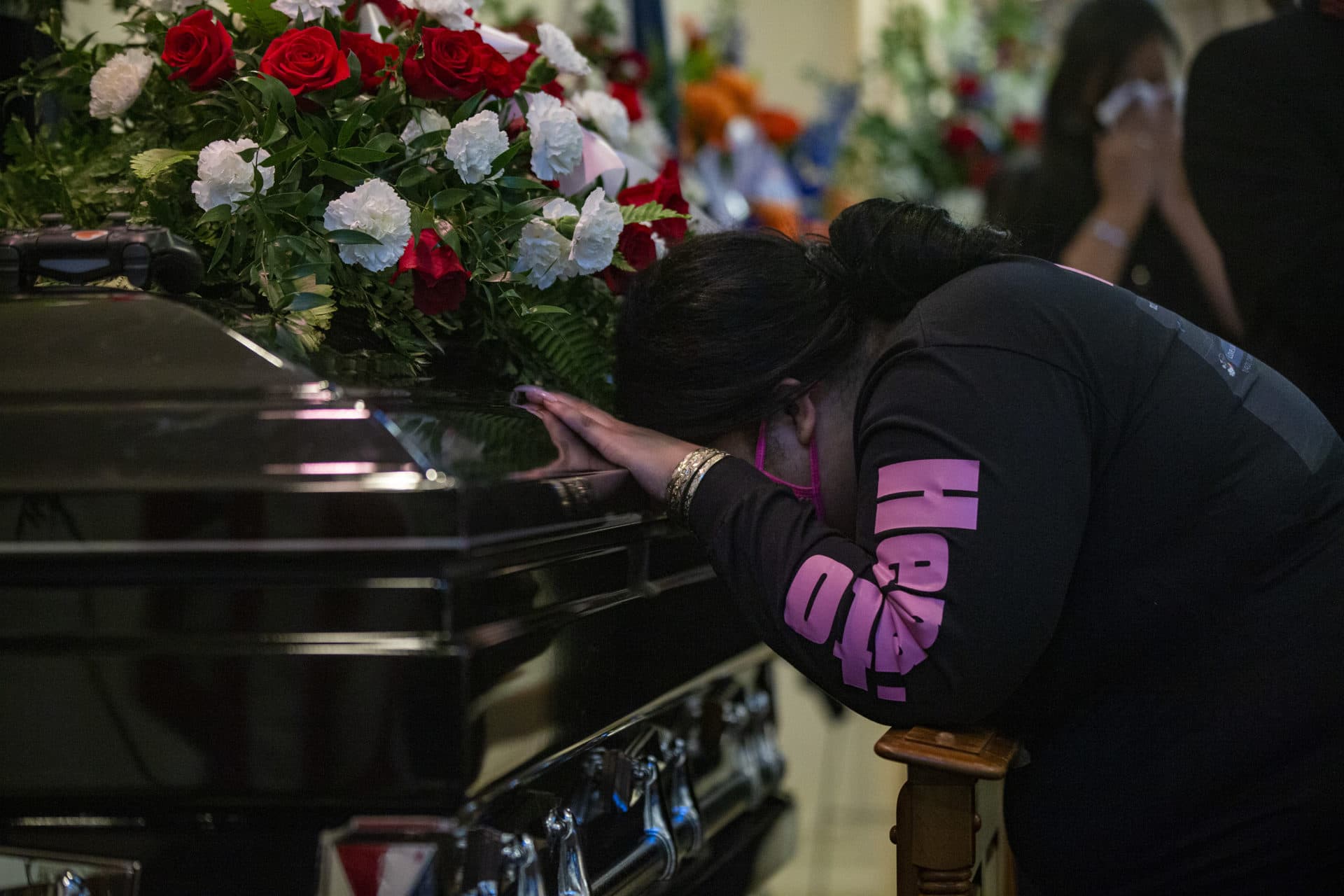 Tina Tapia, Henry Tapia’s sister, grieves as she places her head on his casket. (Jesse Costa/WBUR)
