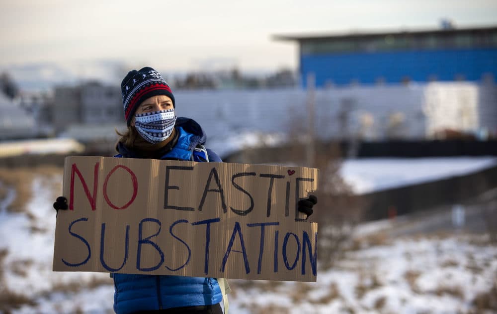 Juliane Manitz of Chelsea at a protest the proposed East Boston electrical substation. The proposed site is the fenced, snow covered area behind her. (Robin Lubbock/WBUR)