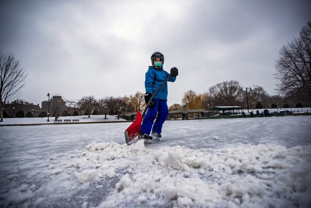 Tanner Li removes snow from the ice of the pond at Boston's Public Garden Monday afternoon for a pick-up hockey game with his friends. (Jesse Costa/WBUR)