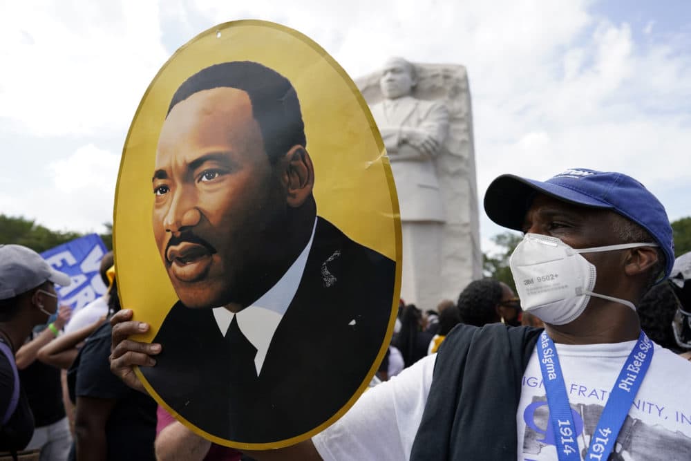 A man holds a photo of Martin Luther King, Jr., at the Martin Luther King Jr. Memorial during the Racial Injustice March on Washington, Friday Aug. 28, 2020, in Washington, D.C. (Carolyn Kaster/AP)