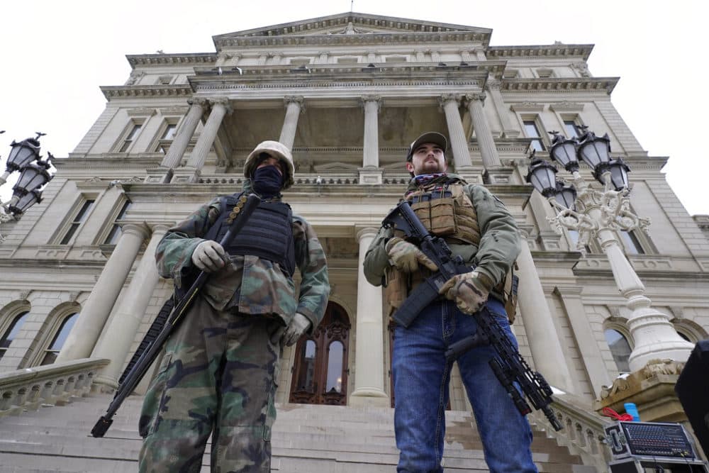 In this Jan. 6, 2021 file photo, armed men stand on the steps at the State Capitol after a rally in support of President Donald Trump in Lansing, Mich. (AP Photo/Paul Sancya, File)