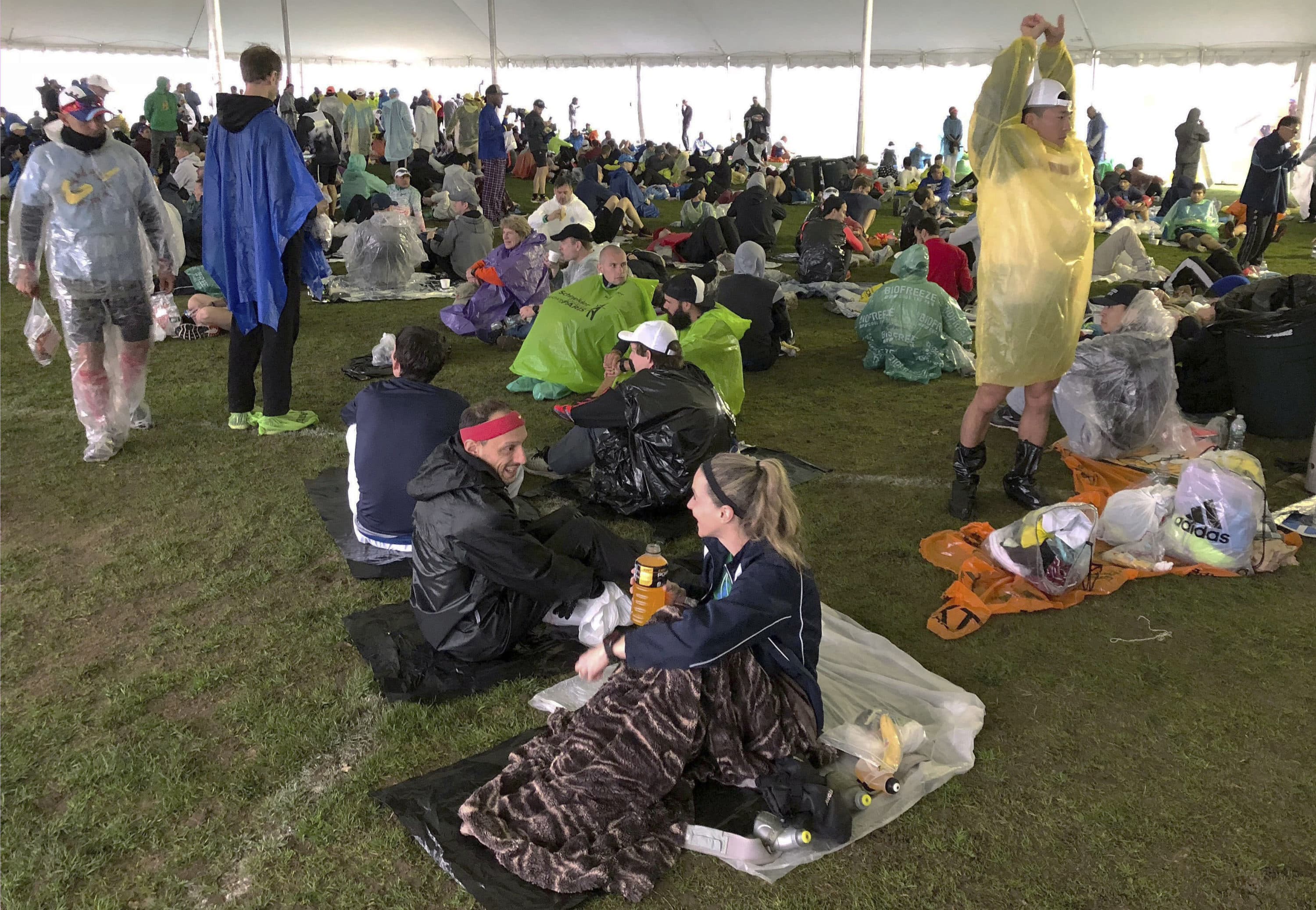 In this April 15, 2019 photo, runners wait under a tent while it rains before the start of the 123rd Boston Marathon in Hopkinton, Mass. (Jennifer McDermott/AP)