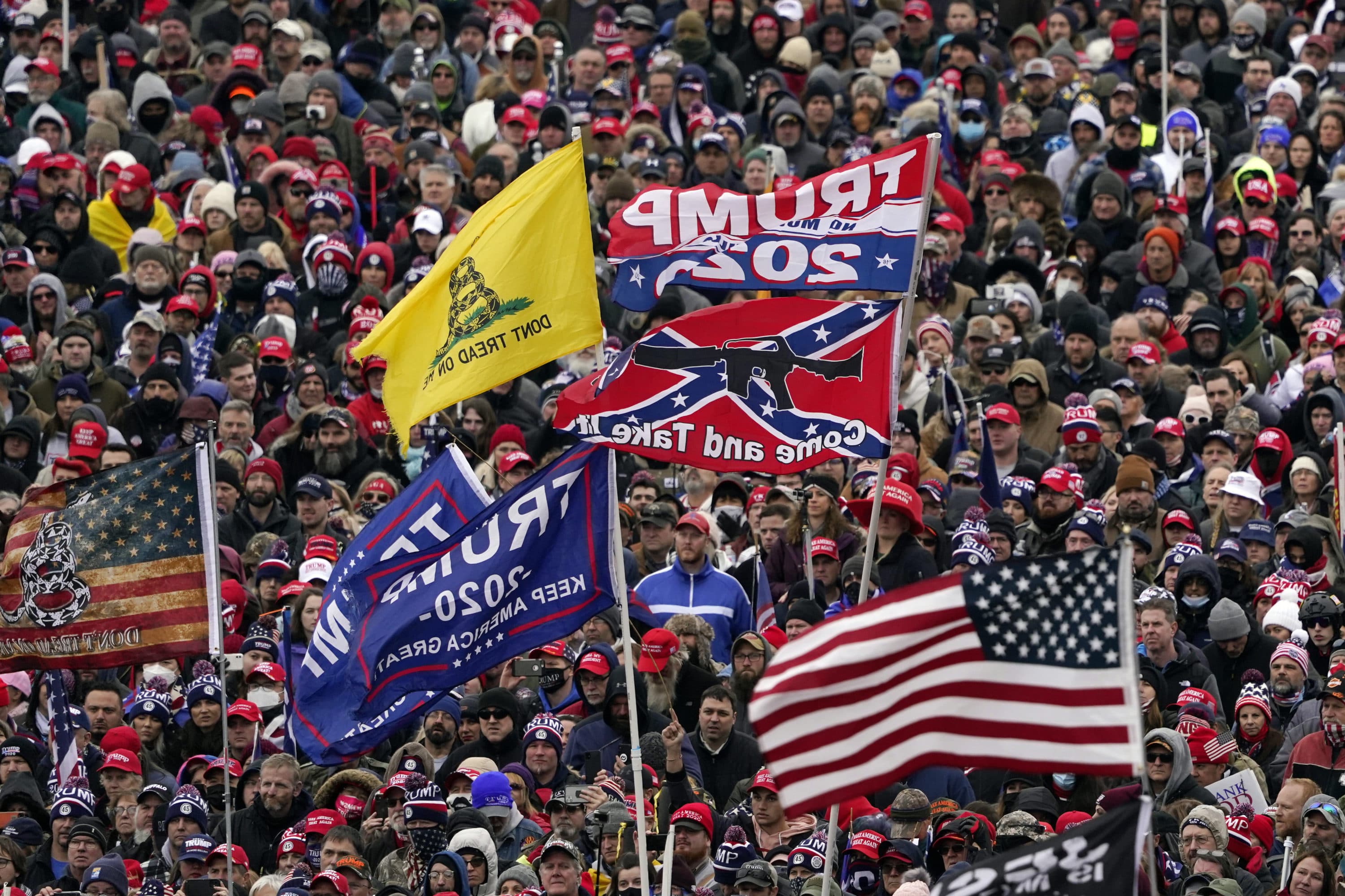 In this Jan. 6, 2021 photo, supporters listen as President Donald Trump speaks as a Confederate-themed and other flags flutter in the wind during a rally in Washington. War-like imagery has begun to take hold in mainstream Republican political circles in the wake of the deadly attack on the U.S. Capitol, with some elected officials and party leaders rejecting calls to tone down their rhetoric contemplating a second civil war. (Evan Vucci/AP)