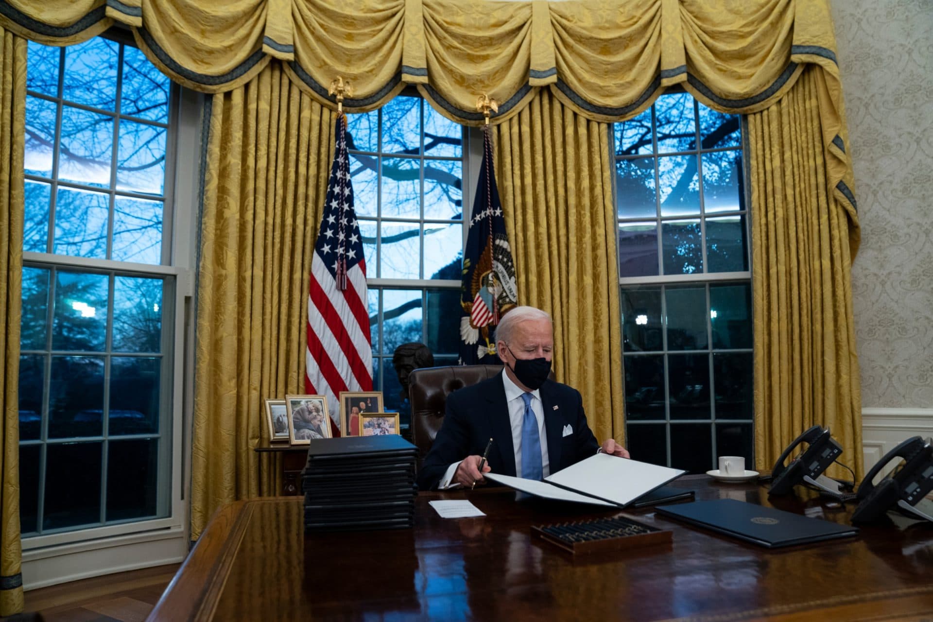 President Joe Biden signs a series of executive orders in the Oval Office on Wednesday night. (Evan Vucci/AP)