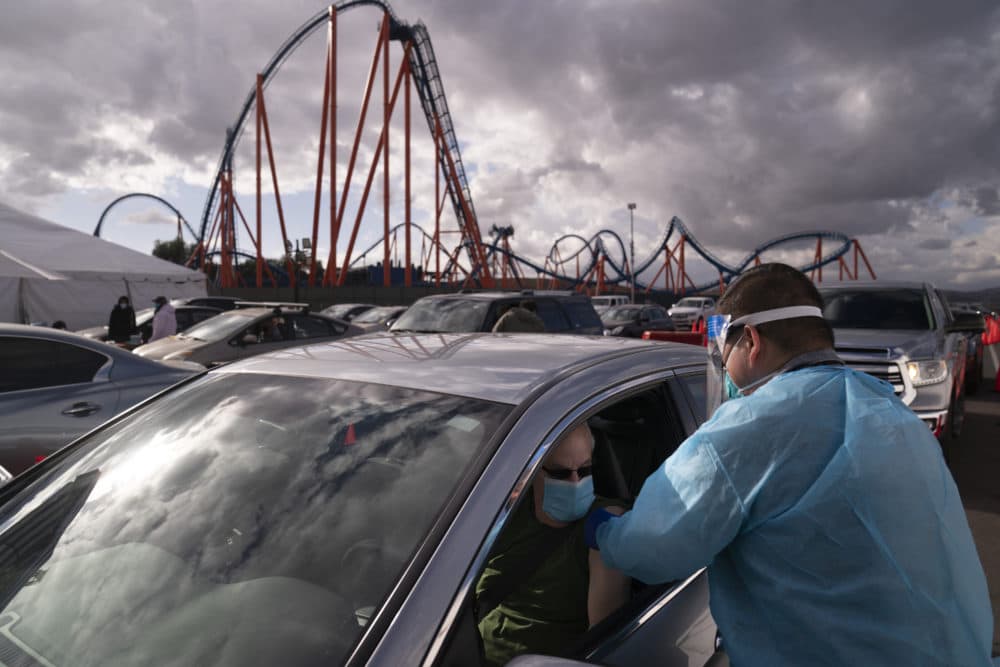 Licensed vocational nurse Joselito Florendo, right, administers the COVID-19 vaccine to Michael Chesler at a mass vaccination site set up in the parking lot of Six Flags Magic Mountain in Valencia, Calif.on Jan. 22, 2021. (Jae C. Hong/AP File)