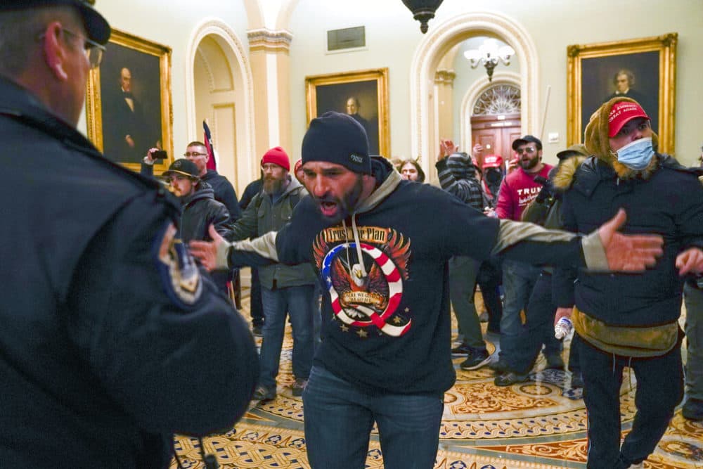 Trump supporters gesture to U.S. Capitol Police in the hallway outside of the Senate chamber at the Capitol in Washington, Wed., Jan. 6, 2021. (Manuel Balce Ceneta/AP)