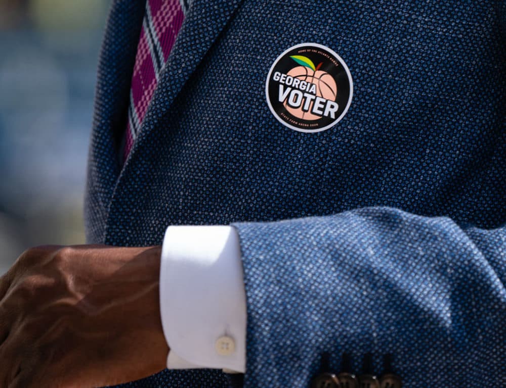 A &quot;Georgia Voter&quot; sticker is seen on the jacket of Democratic U.S. Senate candidate Raphael Warnock after he cast his ballot during early voting on October 21, 2020 in Atlanta, Georgia. (Elijah Nouvelage/Getty Images)