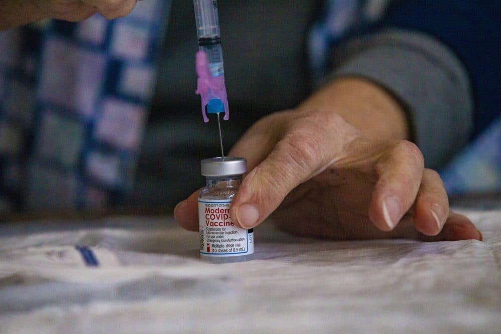 Registered Nurse Delia Murphy dispenses a dose of the Moderna COVID-19 vaccine into a syringe at the Gillette Stadium COVID-19 Vaccination Site. (Jesse Costa/WBUR)