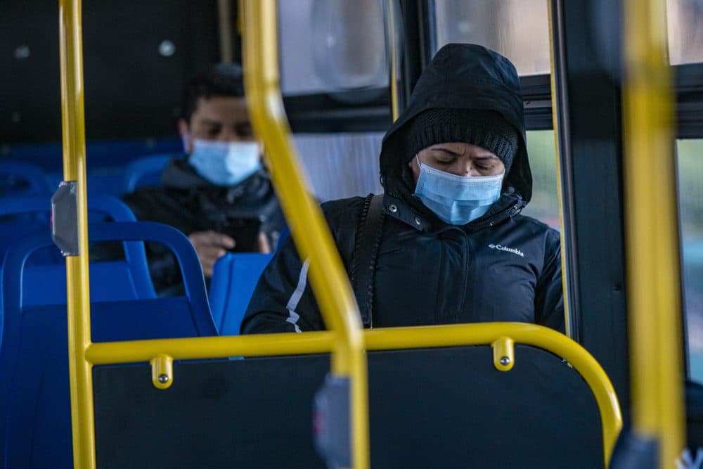 Masked passengers ride an MBTA bus in January. (Jesse Costa/WBUR)