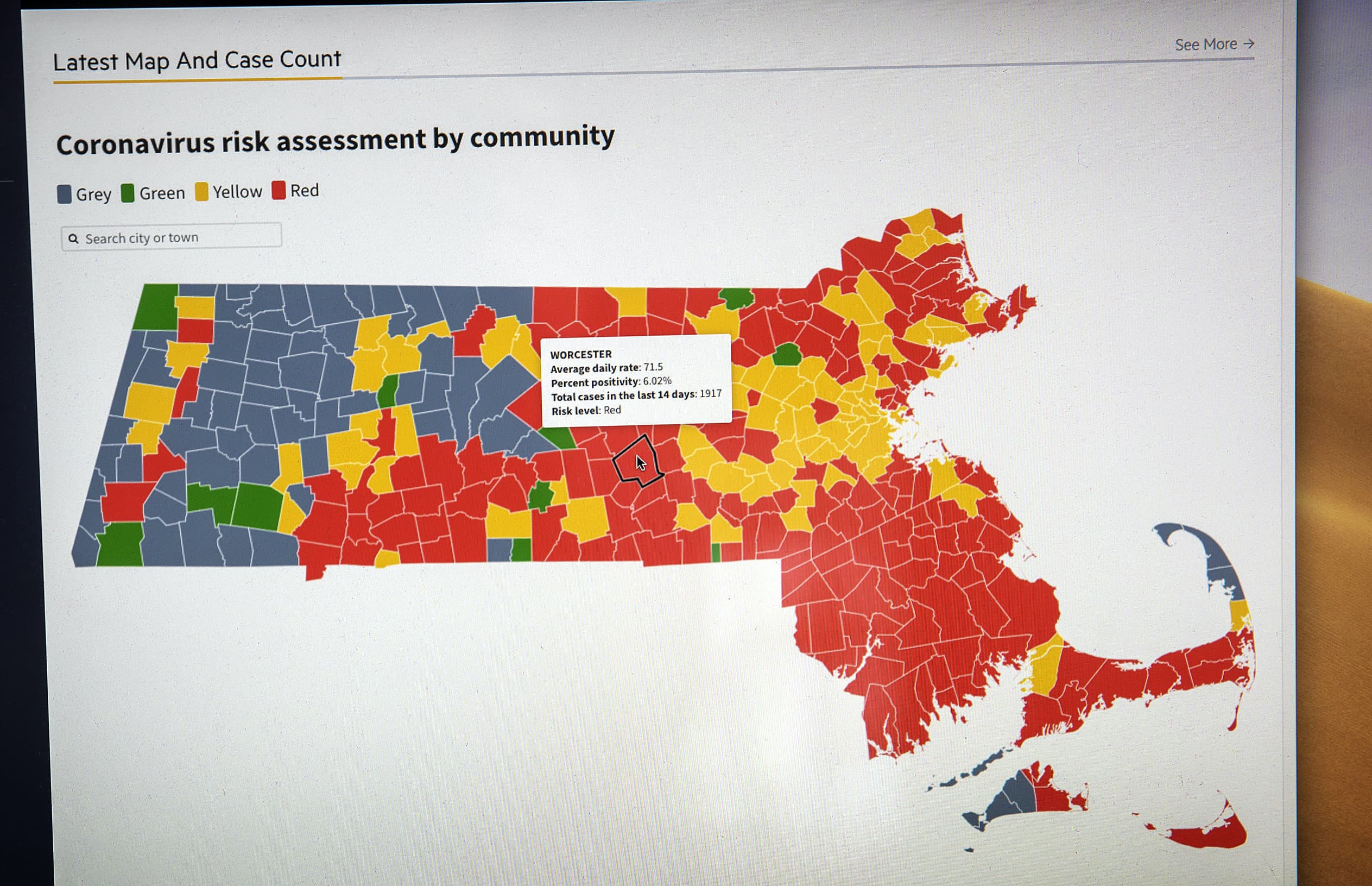 A screen displaying a town-by-town map of Massachusetts, color-coded based on risk level for COVID-19.