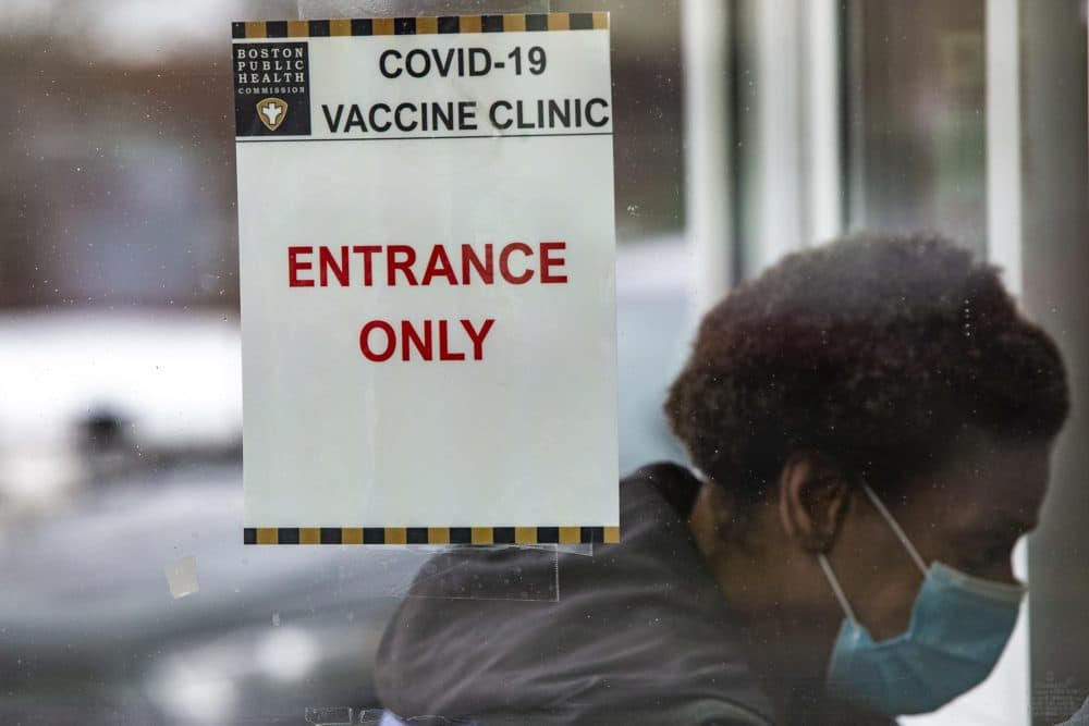 A woman walks through the front entrance of the Reggie Lewis Center to be immunized with the COVID-19 vaccine. (Jesse Costa/WBUR)