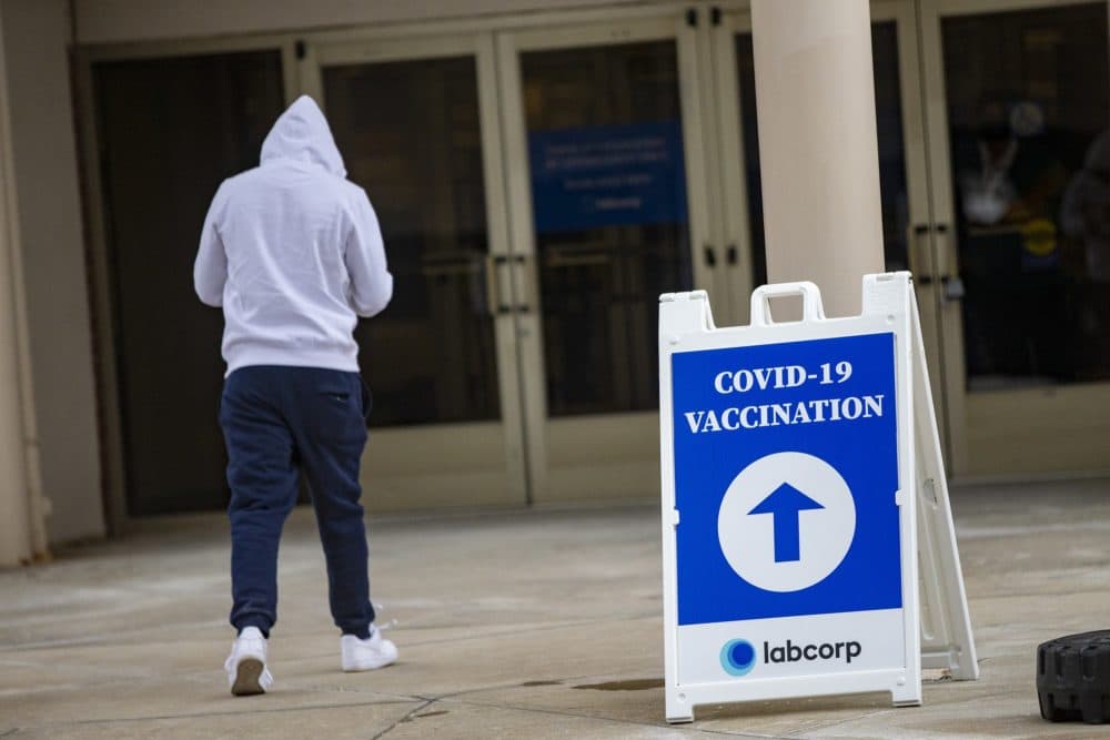 A man walks toward the entrance for the COVID-19 vaccination site at the Natick Mall. (Jesse Costa/WBUR)