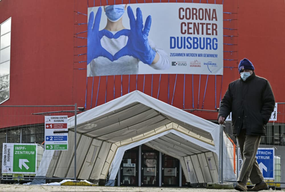 A man wearing a face mask walks past the Corona Center in Duisburg, Germany. The former theater has been turned into a COVID-19 test and vaccination center. Thousands of elderly Germans faced online error messages and jammed up hotlines in late Jan. 2021 as technical problems marred the start of the coronavirus vaccine campaign. (Martin Meissner/AP)