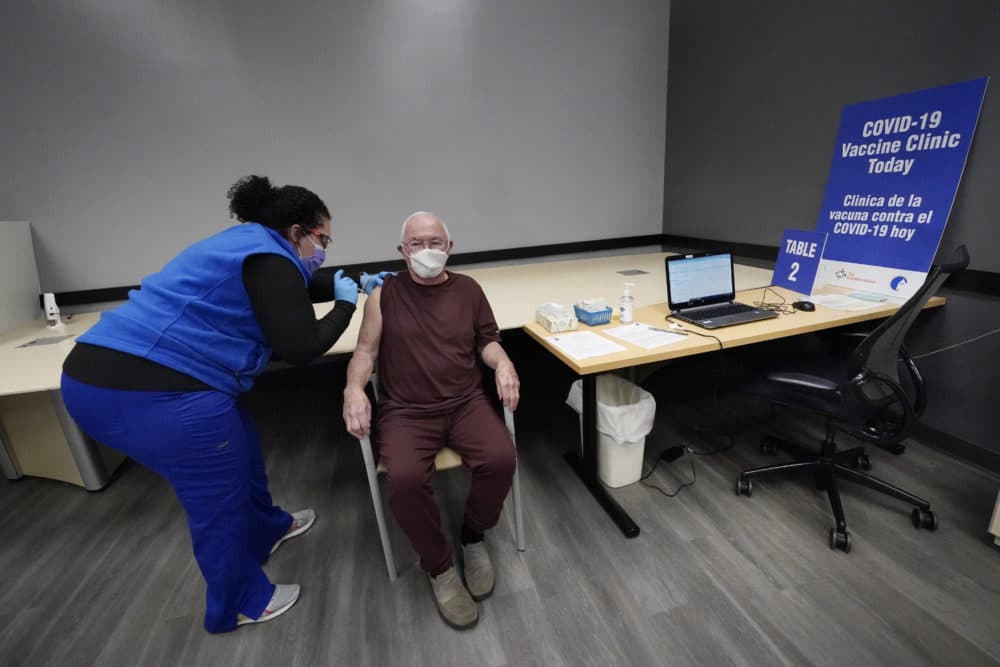 Nurse Maria Maldonado administers a COVID-19 vaccine to 82-year-old David Evans, who had the recently opened vaccination site in Chelsea, Mass., Feb. 10, 2021, mostly to himself. (Elise Amendola/AP)
