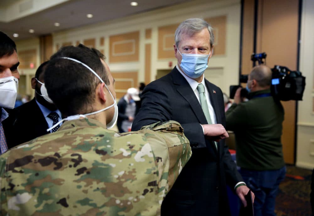 Senior Airman William Borcy, left, greets Gov. Charlie Baker during a tour of the mass vaccination site at the DoubleTree by Hilton Hotel Boston North Shore in Danvers on Feb. 10, 2021. (Jonathan Wiggs/The Boston Globe via Getty Images)