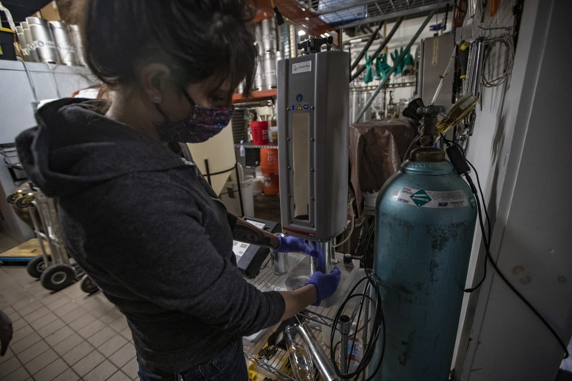 Bone Up Brewing co-owner and brewer Liz Kiraly performs quality control measuring the integrity of the canning, measuring the amount of air inside the can, ensuring its stability and shelf life. (Jesse Costa/WBUR)