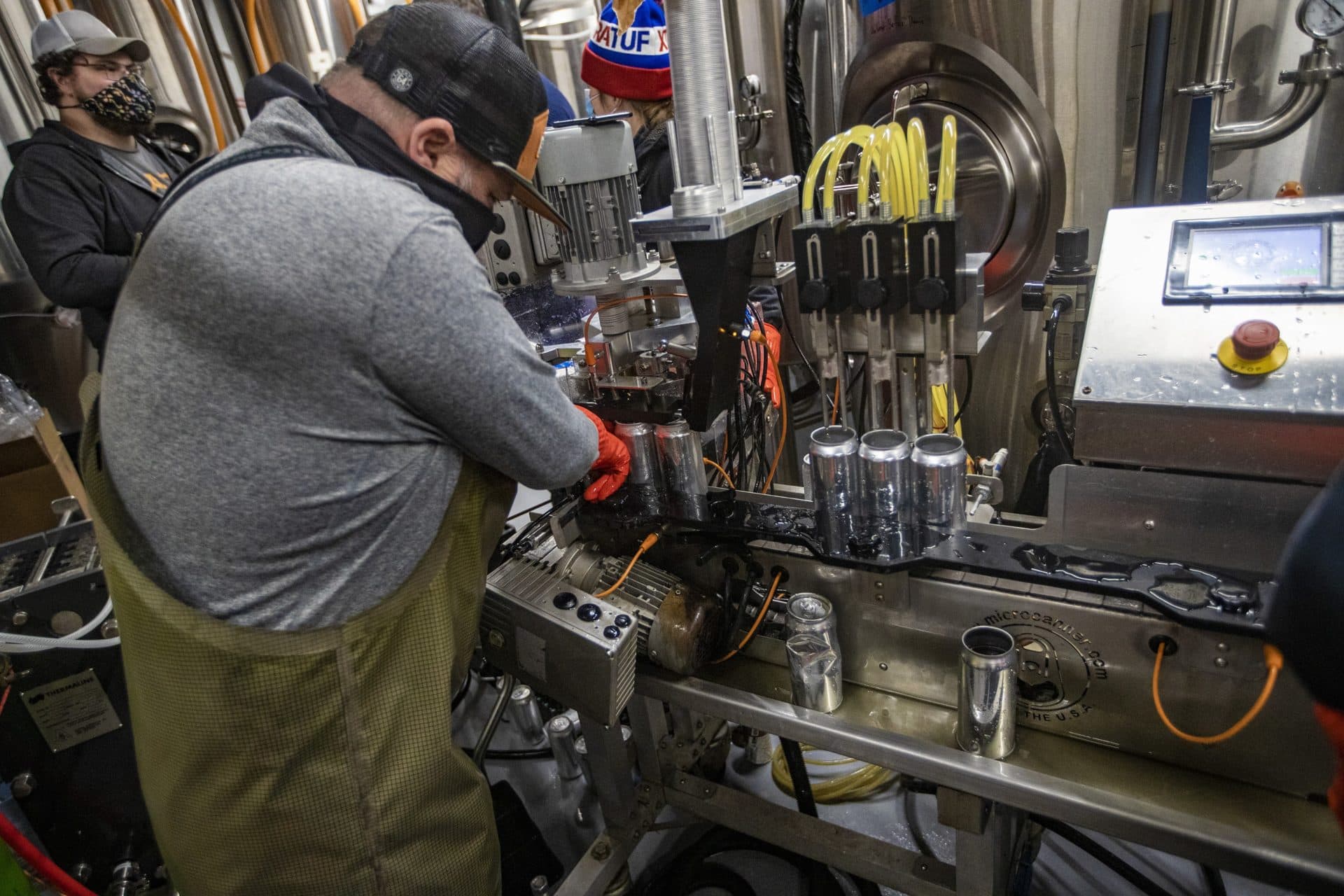 State 64 owner Tim Little works on removing a can that has jammed up in the sealer. (Jesse Costa/WBUR)