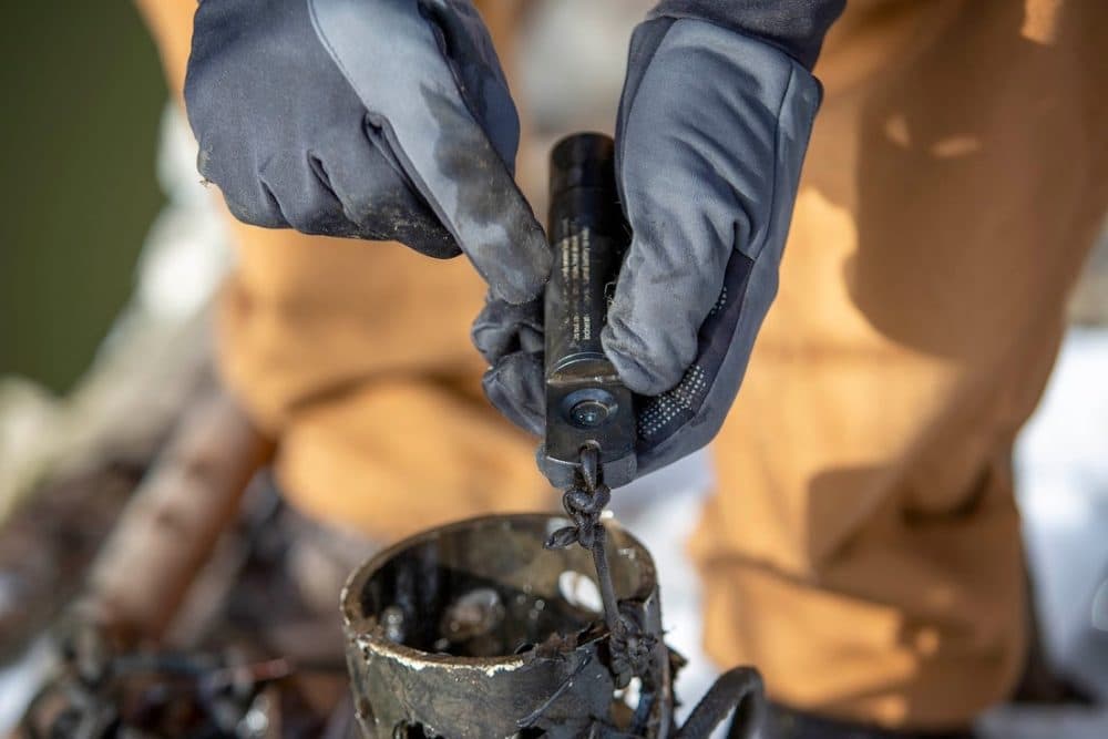 Scientist Andrew Hrycyna cleans off a device for measuring chloride levels in water after retrieving it from Alewife Brook. (Robin Lubbock/WBUR)