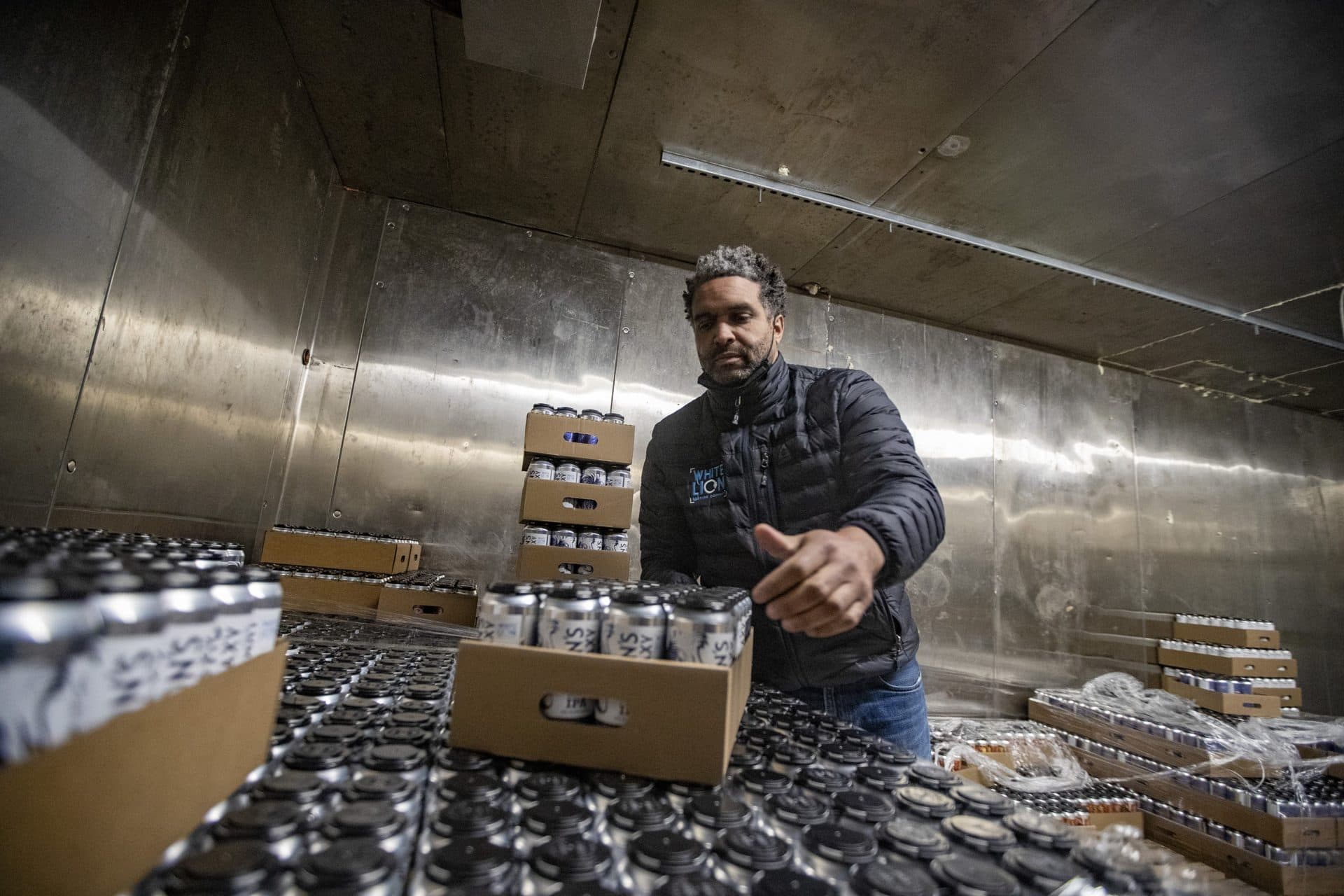 White Lion Brewing owner Ray Berry moves some cases of Lion’s Galaxy IPA in the storage cooler. (Jesse Costa/WBUR)