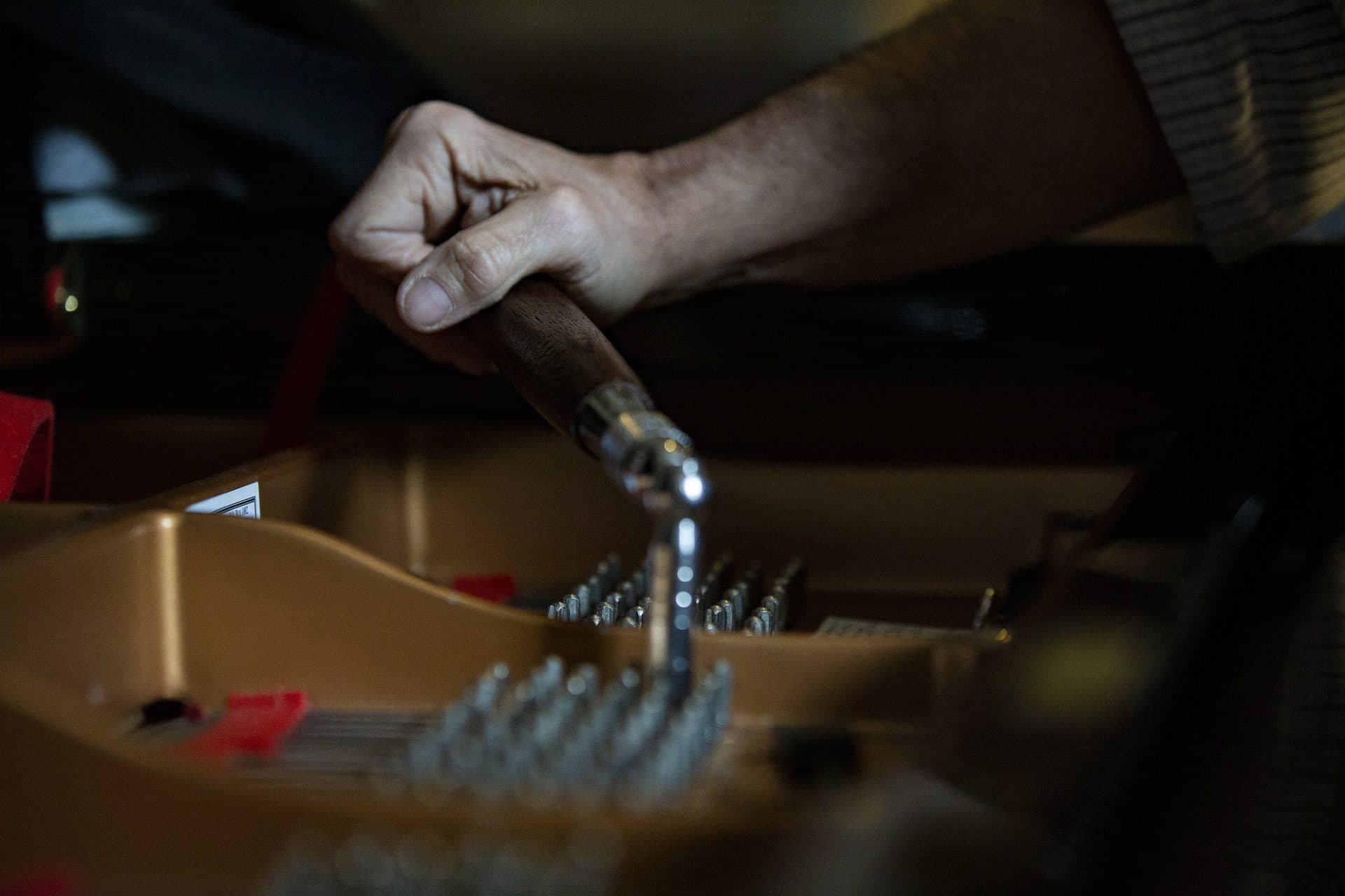 Fred Mudge uses a tuning hammer to tune a Yamaha C7 piano. (Jesse Costa/WBUR)