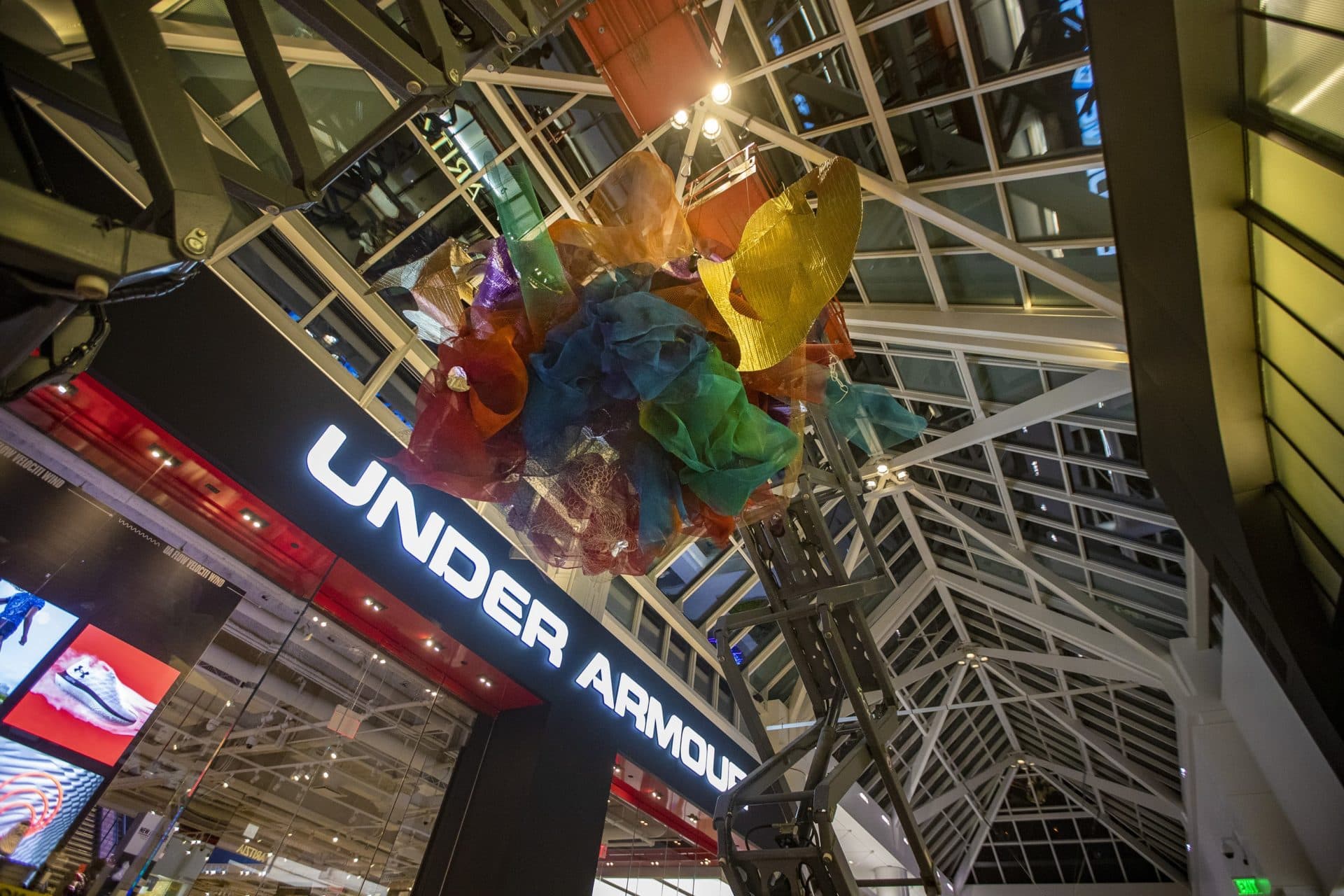 Workers hoist one of three “Astral Beings” to be suspended from the ceiling in the main corridor of the Prudential Center Mall. (Jesse Costa/WBUR)
