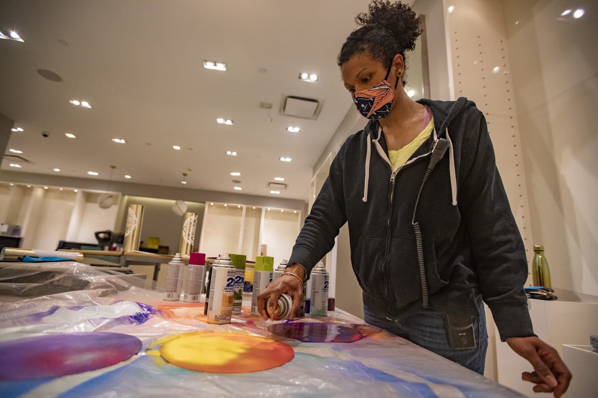 Cicely Carew spray paints discs that will be included for her “Alta Major” piece to be installed in the front entrance of the Prudential Center. (Jesse Costa/WBUR)