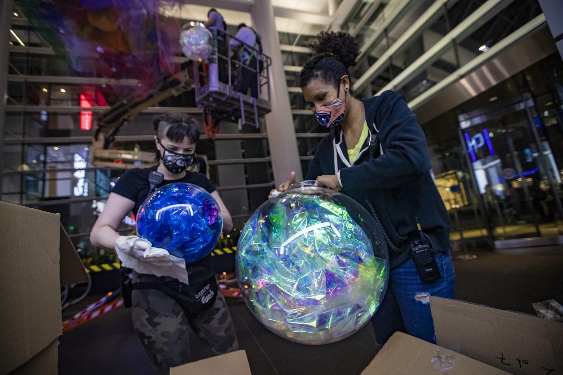 Polina Starobinets (left) and Cicely Carew clean clear globes which will be suspended in the front entrance of the Prudential Center. (Jesse Costa/WBUR)