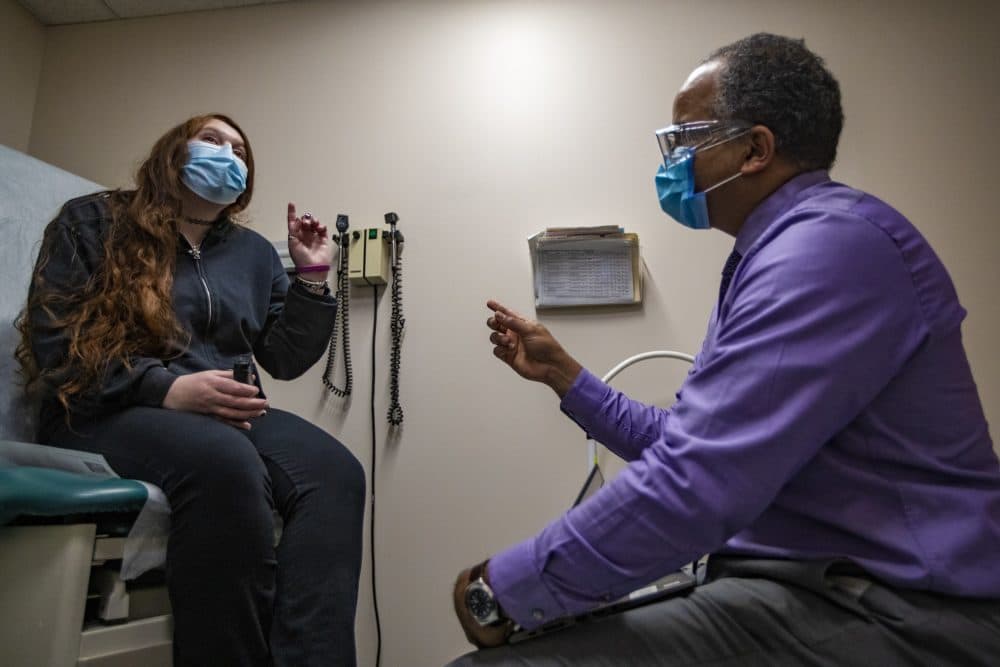 Gabriela Wood consults with Dr. Kiame Mahaniah Chief Executive Officer at Lynn Community Health Center, about whether coronavirus vaccines are safe and whether they interfere with fertility. (Jesse Costa/WBUR)