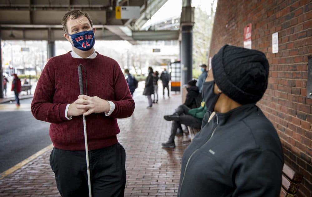 Alex Gray, who is campaigning to become a Boston city councilor, talks with a voter at Forest Hills station. (Robin Lubbock/WBUR)
