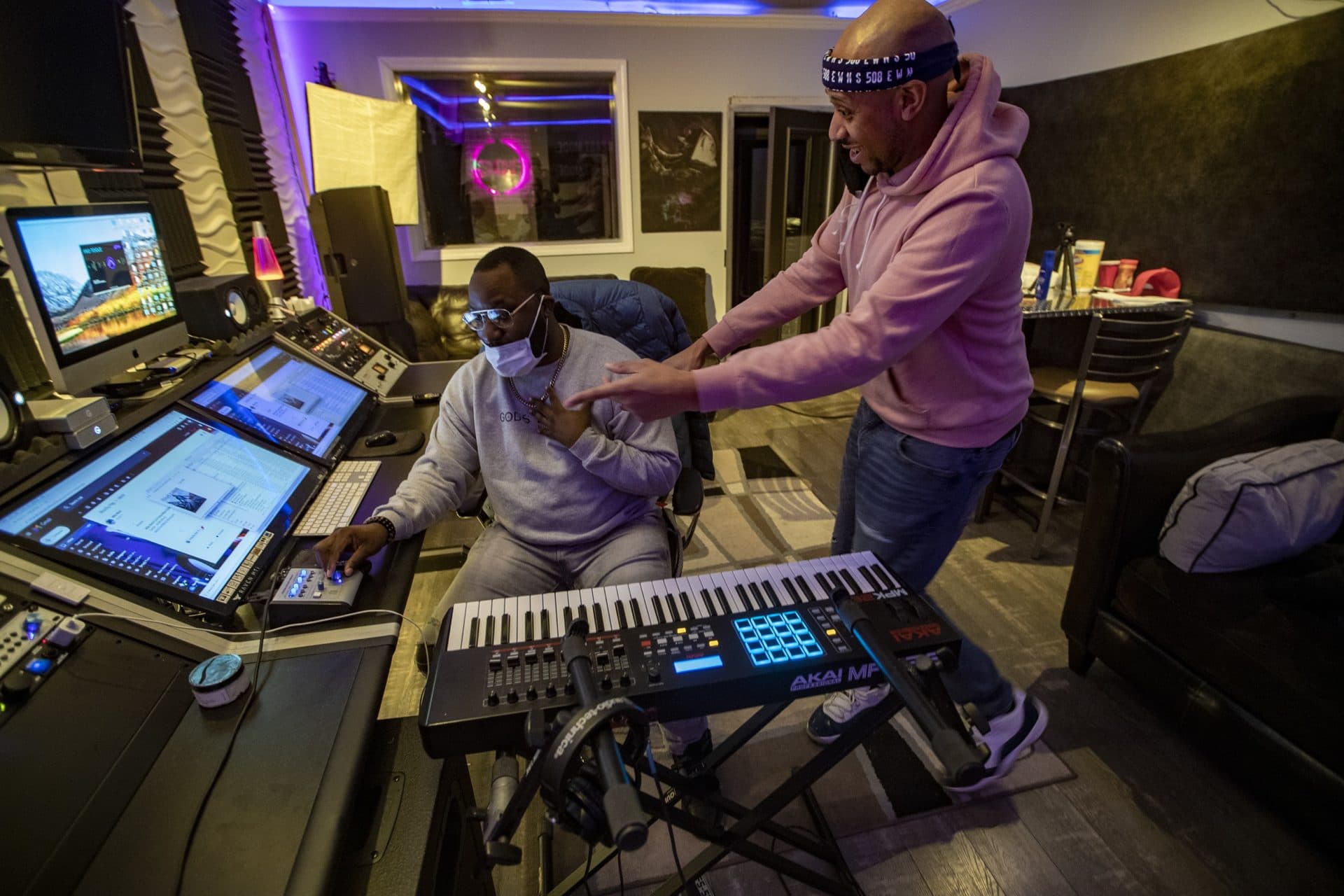 Mike Mack, right, working with International Show, points out a part of a Christian gospel song playing on the board, and suggests a certain singer they know who could perform it. (Jesse Costa/WBUR)