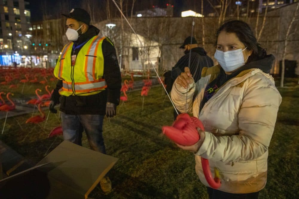 Bessie Villeda assembles a flamingo at the Boston Seaport at the installation gets under way. (Robin Lubbock/WBUR)