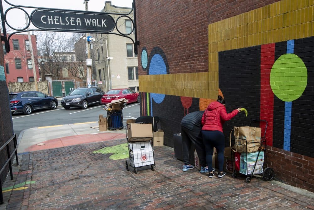 After picking up food supplies from La Colaborativa, Chelsea residents transfer food items from the boxes into carts in the alley of Chelsea Walk. (Jesse Costa/WBUR)