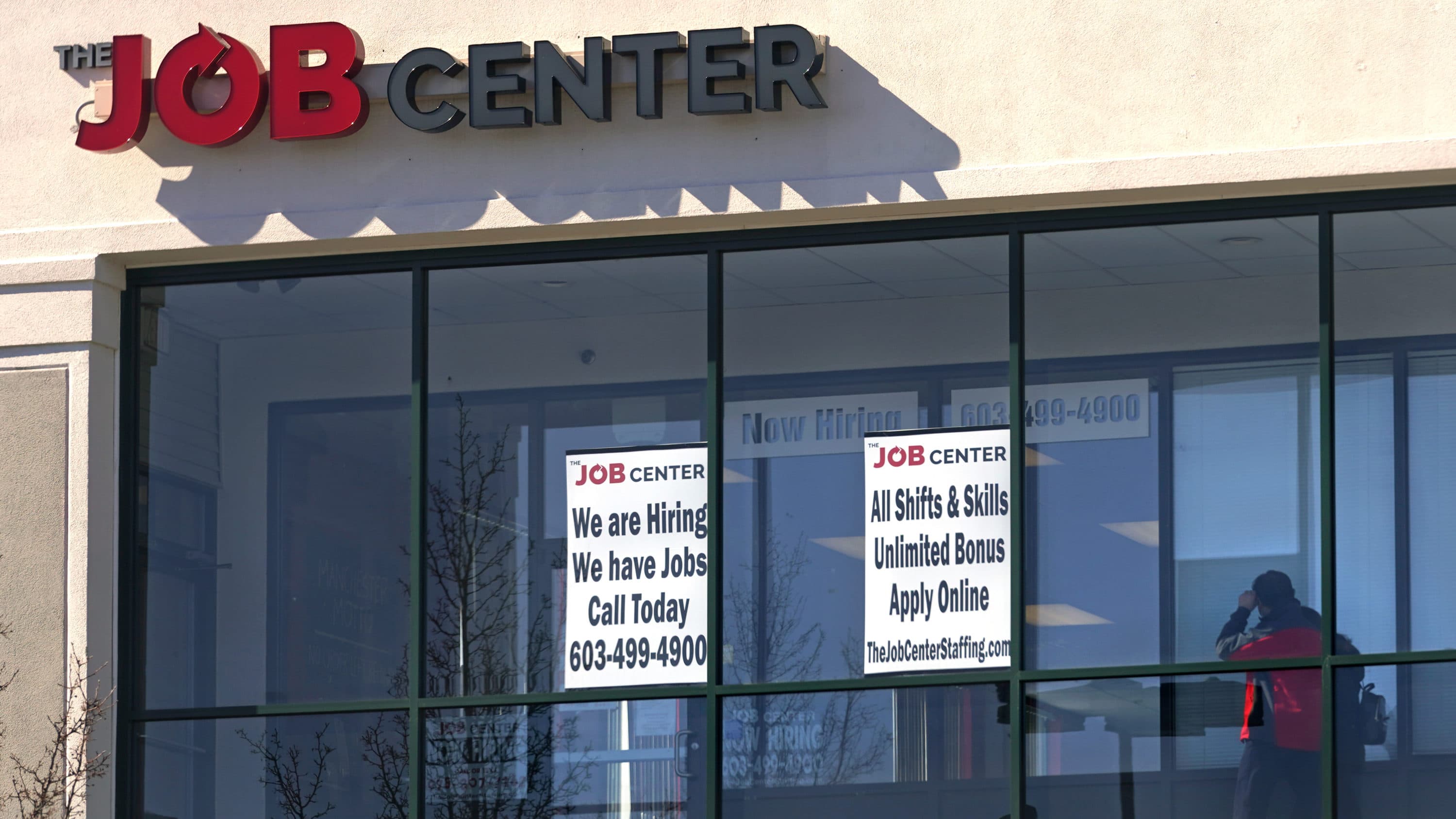 A man walks past the signs of an employment agency, Tuesday, March 2, 2021, in Manchester, N.H. (AP Photo/Charles Krupa)