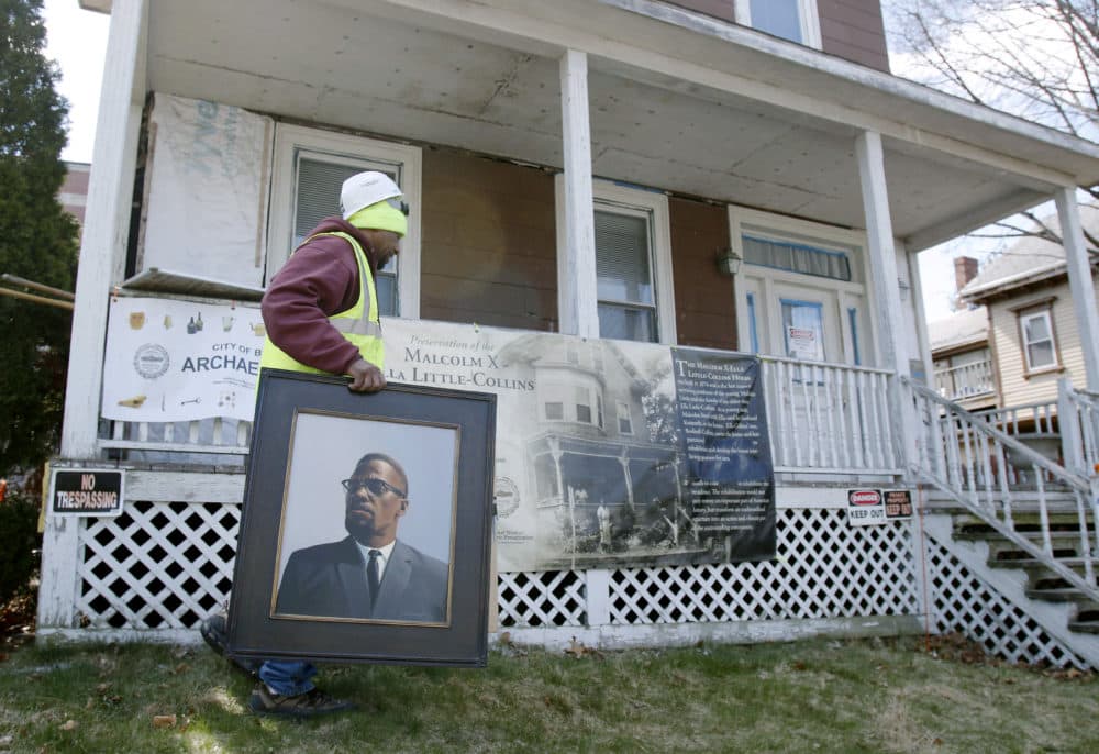 FILE - In this 2016 file photo, Rodnell P. Collins carries a painting of his uncle, Malcolm X outside the house where the slain African-American activist spent part of his teen years in the Roxbury neighborhood of Boston. (Bill Sikes/AP File)
