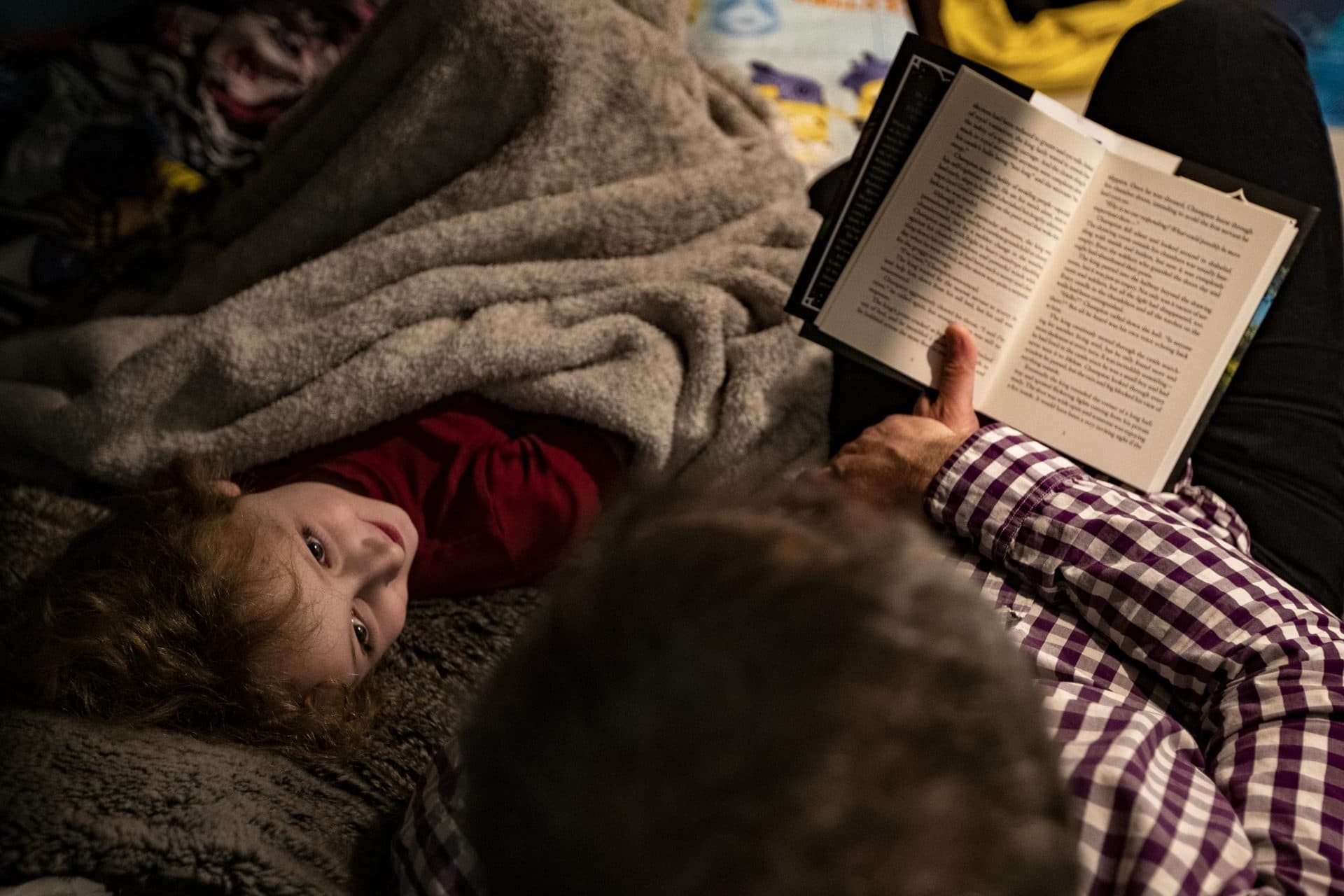 Hallel's father reads them a bedtime story. (Jesse Costa/WBUR)