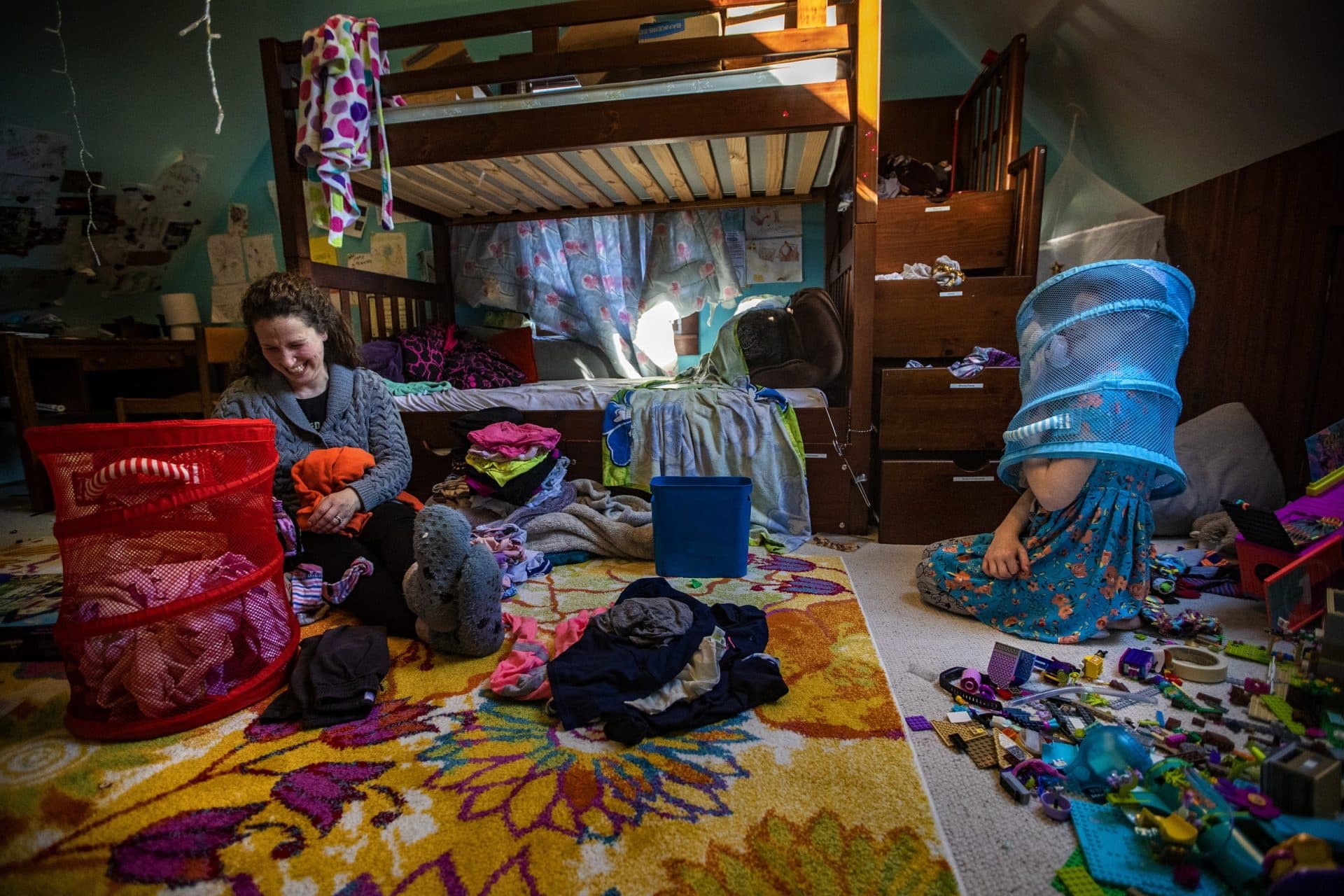 Shira laughs as Hallel places a laundry basket on their head. (Jesse Costa/WBUR)